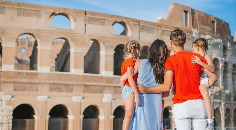 Parents and children looking up at the Colosseum in Rome